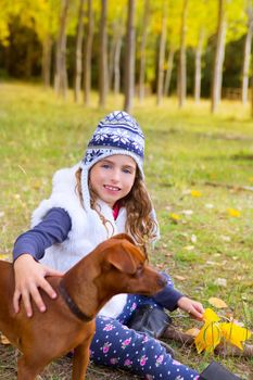 Autumn girl in poplar tree forest playing with dog sitting at meadow