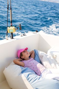 child girl sailing relaxed on boat deck enjoying a nap in blue sea