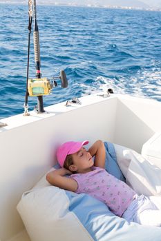 child girl sailing relaxed on boat deck enjoying a nap in blue sea