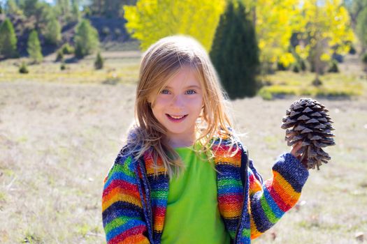 Child little girl holding pine cone in winter fall at nature outdoor