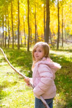 Explorer child girl with tree branch in poplar golden yellow trees autumn forest