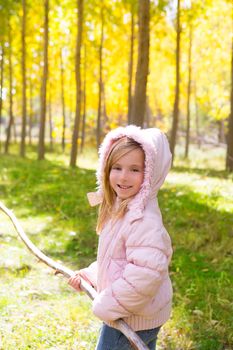 Explorer child girl with tree branch in poplar golden yellow trees autumn forest