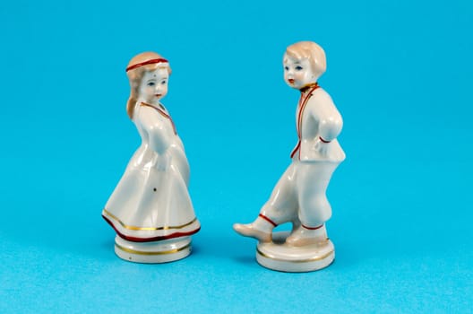 two ceramic toy decor dancers statue boy and girl on blue background.