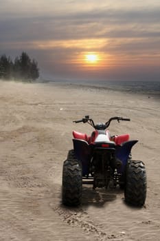 A beach buggy bike on the sand at a beautiful beach at sunset.