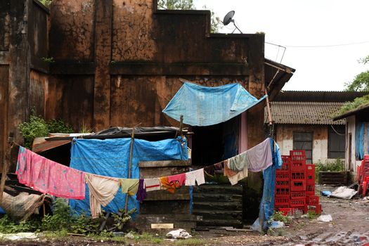 A exterior view of a dirty house and its surroundings in an Indian slum.