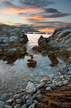 HDR photo of sea, rocks and sunrise sky with clouds in Kaikoura, New Zealand.