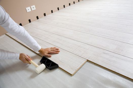  Worker laying a floor with laminated flooring boards 