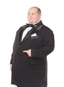 Elegant very fat man in a dinner jacket and bow tie winking mischievously and pointing with his finger across his belly , three quarter studio portrait on white
