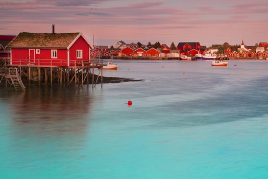 Typical red rorbu fishing hut in town of Reine on Lofoten islands in Norway lit by midnight sun