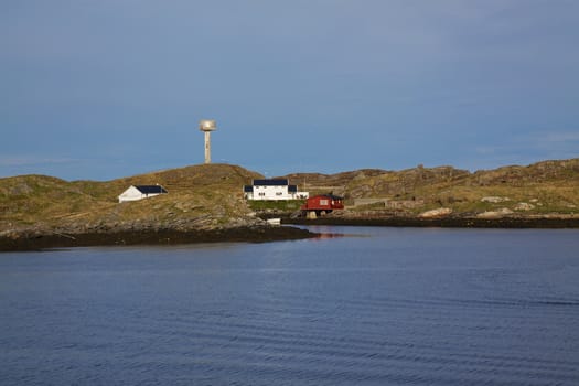 Scenic rocky coastline of island Rost in Norway with houses and old lighthouse