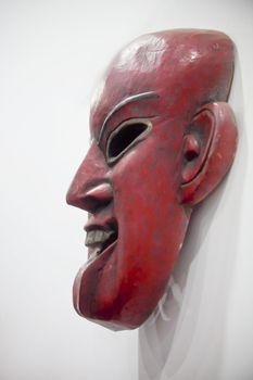 Vertical take of a generic mounted hand carved smiling mask. Shot location India