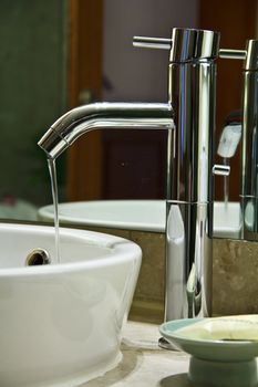 Silver chrome bathroom tap faucets running water in a sink