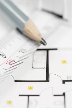 White tape measure on architect plans with pencil.