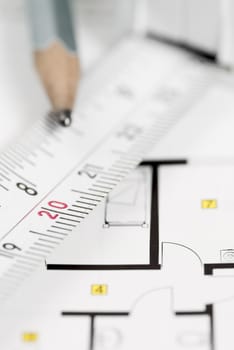 White tape measure on architect plans with pencil.