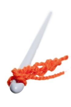 Crochet hook with orange wool. White background.