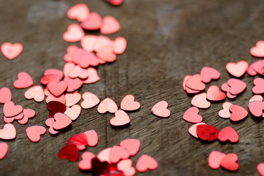 A heart made of chocolat on a old wooden table with small glitter hearts