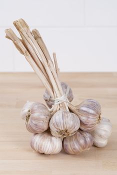 Bunch of tied garlic on wooden kitchen work surface.