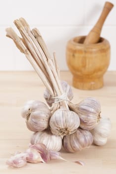 Bunch of tied garlic on wooden kitchen work surface.