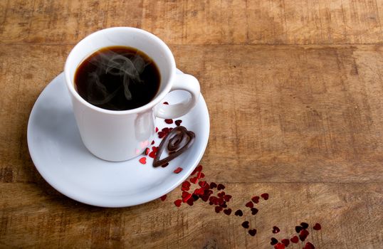 Coffee cup with glitter hearts on a old wooden table