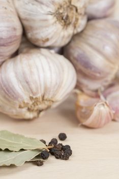 Garlic, Peppercorns, Bay Leaves on wooden kitchen surface.