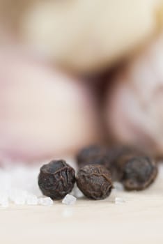 Garlic cloves, peppercorns & salt on wooden surface.