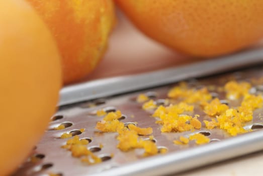 Grater and citrus zest on wooden kitchen surface.