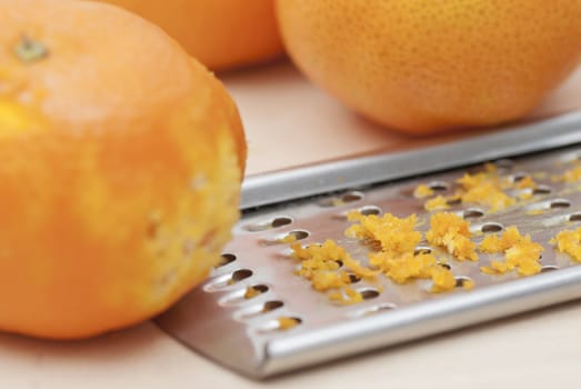Grater and citrus zest on wooden kitchen surface.