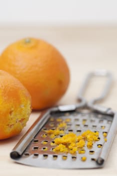 Grater and citrus zest on wooden kitchen surface.