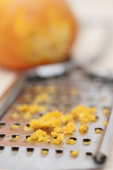 Grater and citrus zest on wooden kitchen surface.