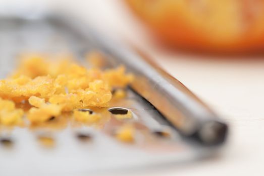 Grater and citrus zest on wooden kitchen surface.