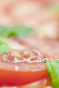 Macro image of slices of Tomato prepared with oilive oil, basil, pepper & salt.