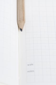 Pencil resting on blank squared note paper.