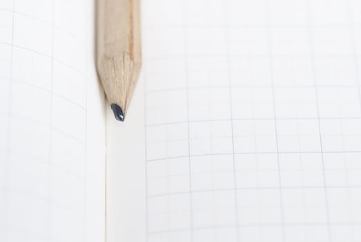 Pencil resting on blank squared note paper.