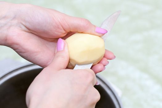 Hands with knife cut the potatoes into the pot