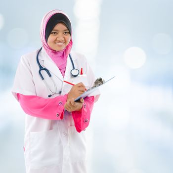 Southeast Asian Muslim medical student. Young medical doctor woman standing on hospital background.