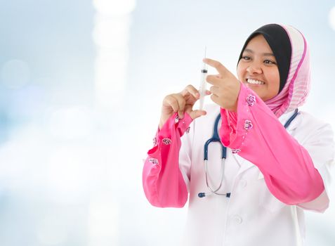 Muslim female medical doctor filling the syringe getting ready for a medical procedure, hospital blue background