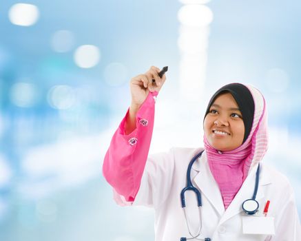 Southeast Asian Muslim medical student sketching on transparent screen, hospital blue background