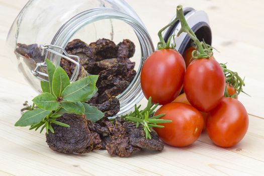 dried tomatoes in a jar and fresh tomatoes
