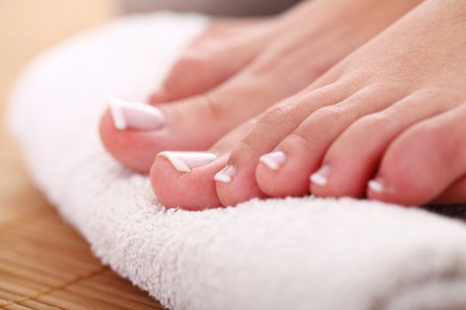 Beautiful foot with french pedicure on white towel