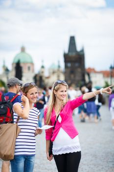 Two female tourists walking along the Charles Bridge while sightseeing in Prague, the historical capital of the Czech Republic (color toned image; shallow DOF)