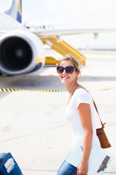 Departure - young woman at an airport about to board an aircraft on a sunny summer day