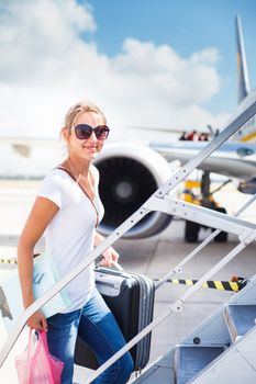 Departure - young woman at an airport about to board an aircraft on a sunny summer day