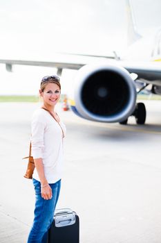 Just arrived: young woman at an airport having just left the aircraft