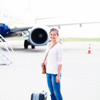 Just arrived: young woman at an airport having just left the aircraft