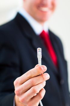 Young businessman holding an ethernet cable - stressing the importance of fast and reliable internet connection for a business (color toned image; shallow DOF)