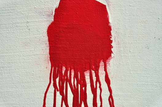 Red paint drips over textured white wall. Abstract background.