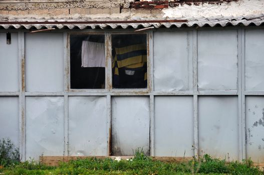 Rusty warehouse tin shack and window with drying clothes.