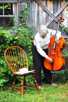 Mature female cellist with her instrument outside.