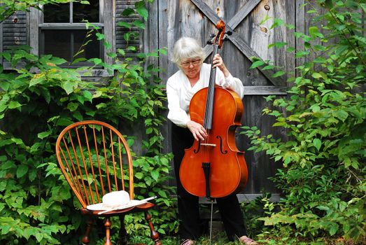 Mature female cellist with her instrument outside.