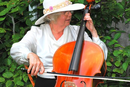 Mature female cellist with her instrument outside.